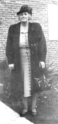 An old black and white photo of a woman in a coat and hat.