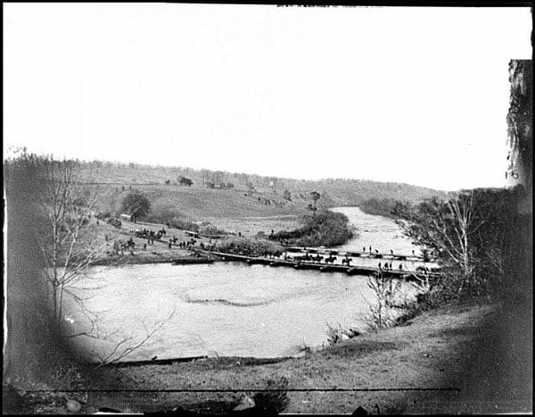 A black and white photo of a river with boats on it.