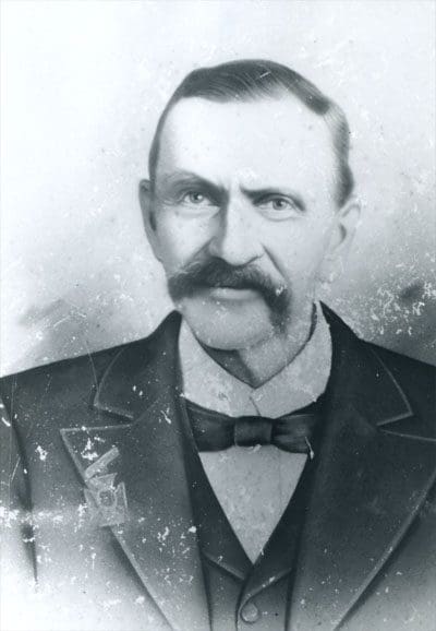 A man with a mustache and beard wearing a suit.