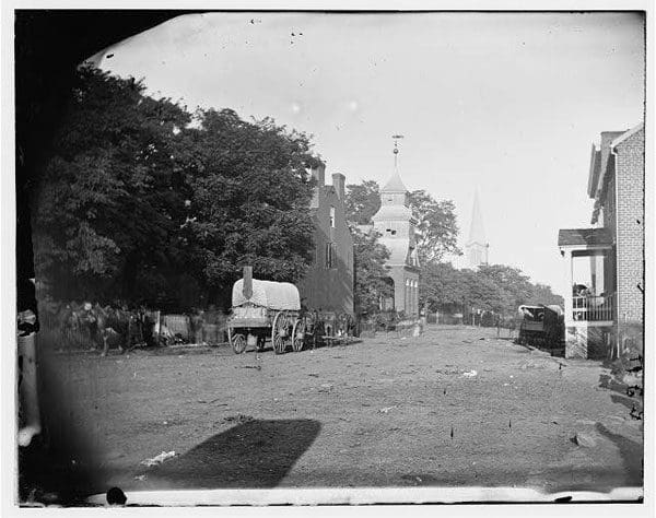 An old photo of a street with a church in the background.