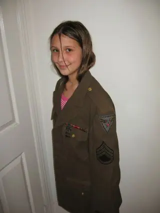 A girl in uniform standing next to a door.