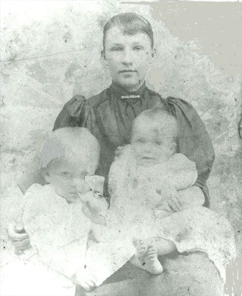 A woman and two children in an old photo.