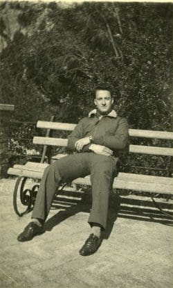 A man sitting on top of a wooden bench.