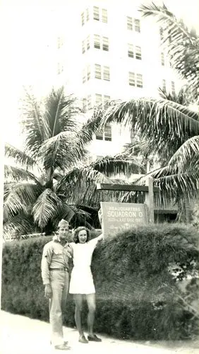 A man and woman standing in front of palm trees.