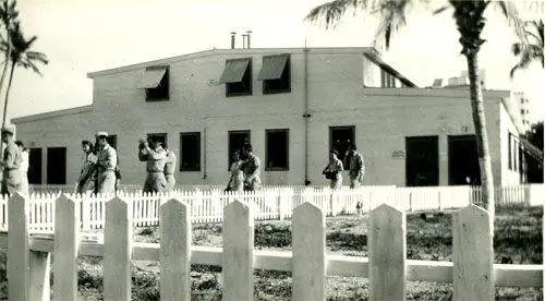 A black and white photo of people in front of a building.