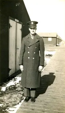 A man in military uniform standing on the sidewalk.