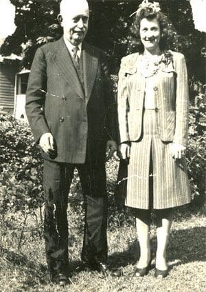 A man and woman standing in front of bushes.