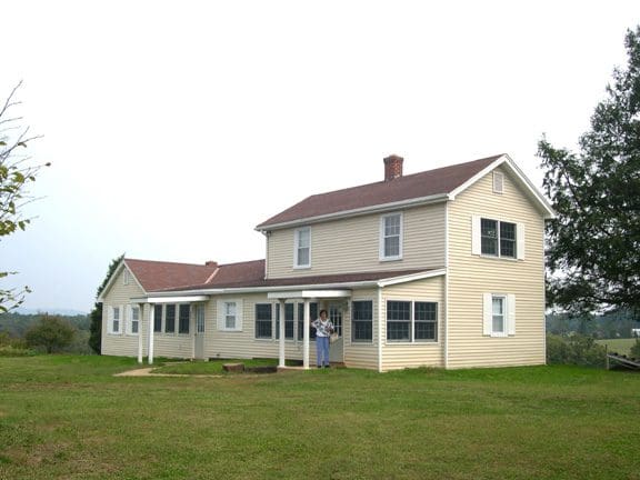 A large white house sitting in the middle of a field.