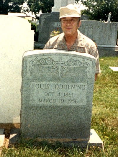 A man standing next to a grave marker.