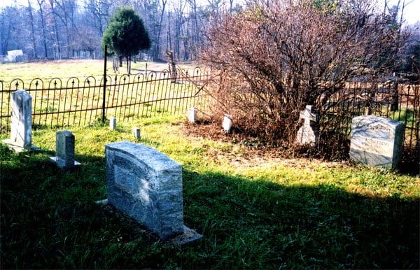 A cemetery with a stone grave and fence.