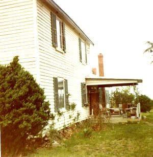 A house with a porch and a tree in the yard.