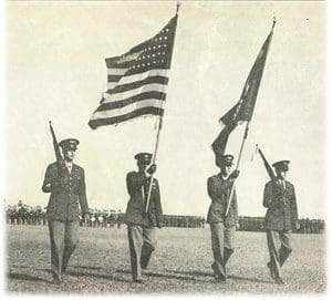 A group of men holding flags in front of a field.