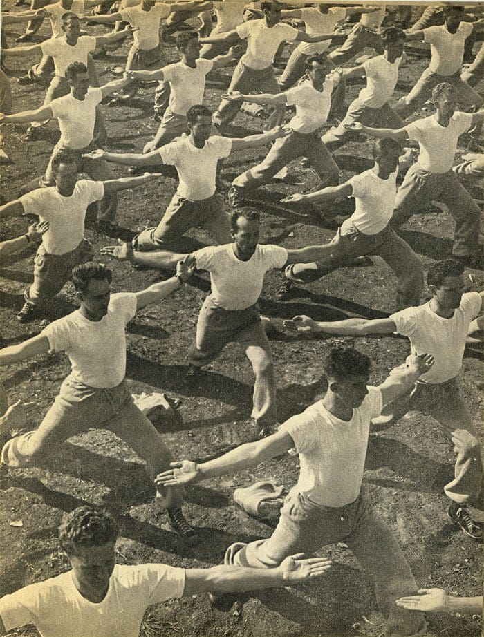 A group of men in white shirts doing yoga.