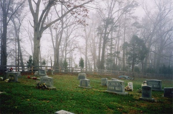 A cemetery with many headstones in the grass.