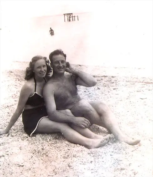 A man and woman sitting on the beach.