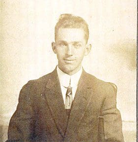 A man in suit and tie standing next to a wall.