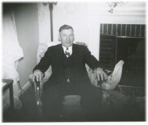 A man in suit and tie sitting on chair.