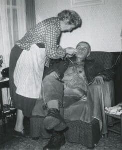 A woman is helping an old man to put something on his face.