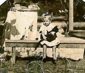 A young girl sitting on top of a wooden bench.