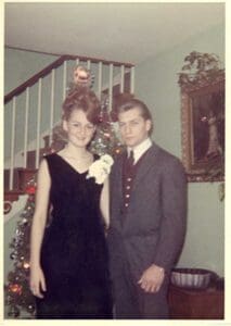 A man and woman pose for the camera in front of christmas decorations.