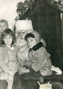 A man dressed as santa claus with two children.