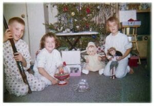 A group of children sitting around in front of a christmas tree.