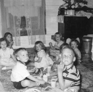 A group of children sitting on the floor in front of a fireplace.