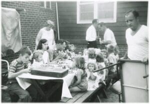 A group of people sitting around a table with cake.