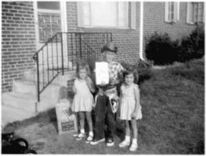 A man holding an envelope with two girls standing next to him.