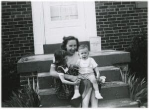 A woman sitting on the steps with two children.