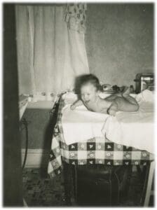 A baby is laying on the table in front of a window.