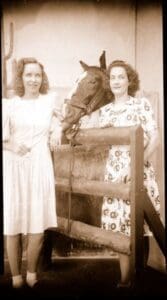 A man and two women standing next to a horse.