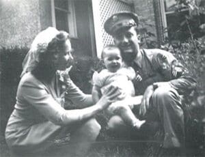 A man and woman holding a baby in front of a building.