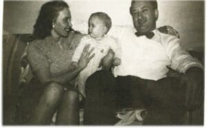 A man and woman holding a baby in front of another man.