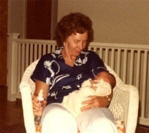 A woman holding a baby while sitting in a chair.