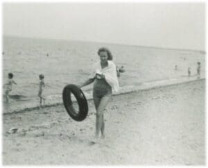 A woman holding an inflatable ring on the beach.