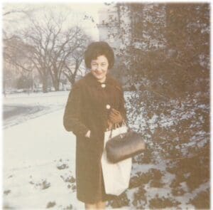 A woman in a brown coat holding a purse.