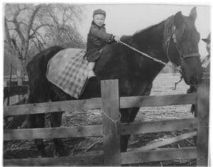 A young boy is sitting on the back of a horse.