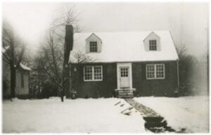 A black and white photo of a house in the snow.