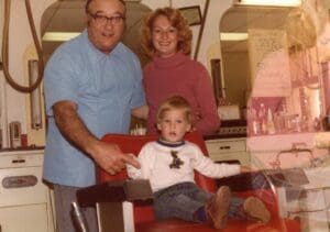 A man and a woman sitting in a barber chair.